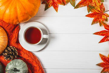  Cup of tea, autumn leaves and pumpkins on a white wooden background, copy space for text. Cozy and warm autumn flatlay