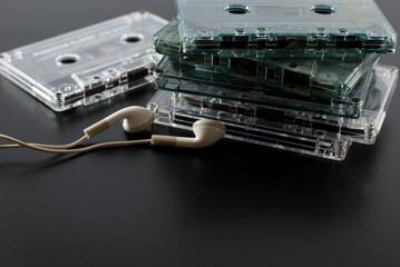 Set of old audio cassettes with earphones on a black floor.