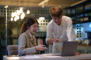 Businessman and businesswoman together and discuss problems in the office using laptop and take note.
