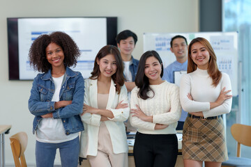 Young businessman and a beautiful Asian businesswoman stand with her arms crossed and pose for a beautiful team photo in the company.