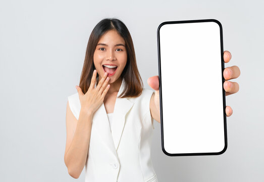 Studio shot of Beautiful Asian woman holding smartphone mockup of blank screen and smiling on white background.