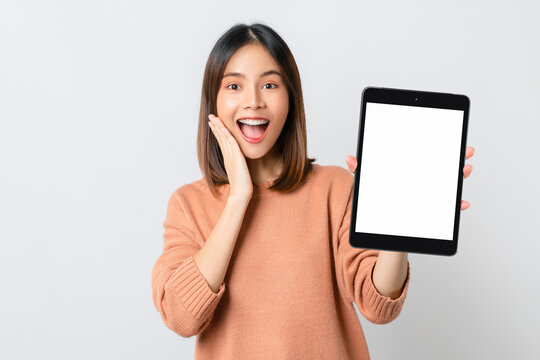 Studio shot of Beautiful Asian woman holding digital tablet mockup of blank screen and smiling on white background.