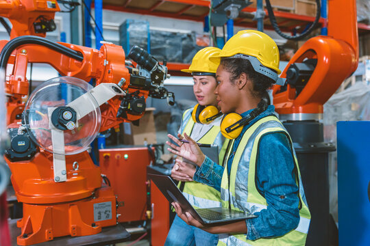 Women engineer worker working team training together at work in modern advanced robot welding machine factory.