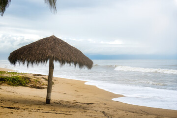 Fototapeta na wymiar Background landscape with umbrella of palm leaves on the beach