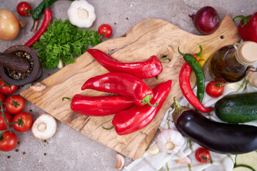red pepper on wooden cutting board and vegetables at domestic kitchen