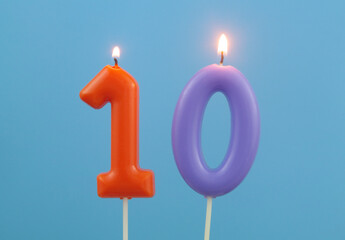 Burning birthday candles on blue background, number 10