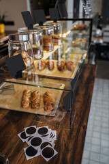 Shot of bar of coffee shop there are sweets croissants and coffee in daytime.