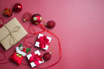 Christmas gift box with decorations over the red background with copy space. 