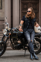 Plakat Portrait of guy looking like macho posing with motorbike outdoors.