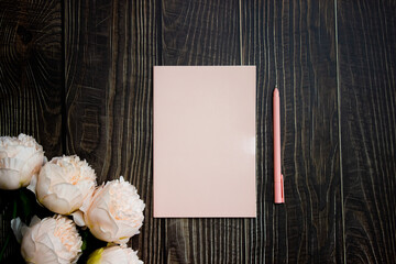 Pink notebook with roses over the wooden table. 