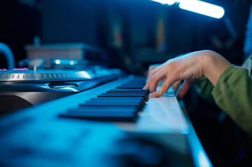 Closeup of keyboardist musician in neon light recording studio