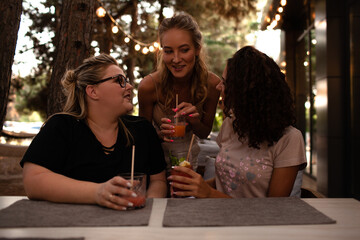 Group of female friends, plus size with thin girls sit in cafe and drink the drinks.
