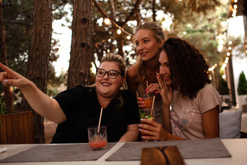 Group of female friends, plus size with thin girls sit in cafe and drink the drinks.