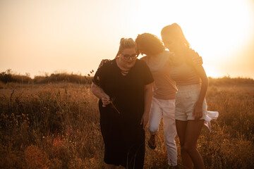 group pf three friends, plus sizewith two thin girls spend happy time together in the nature. Beautiful overweight and strong women have fun, enjoy the momet of sunset .