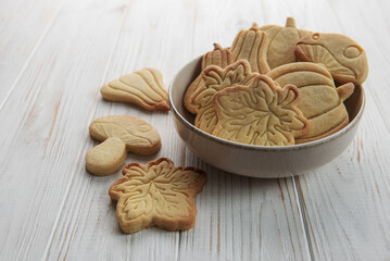 Cookies shaped like pumpkin and leaves on rustic wood background