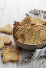Cookies shaped like pumpkin and leaves on rustic wood background