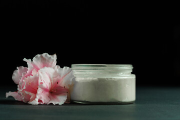 side view of a jar of body butter with pink rhododendron flower