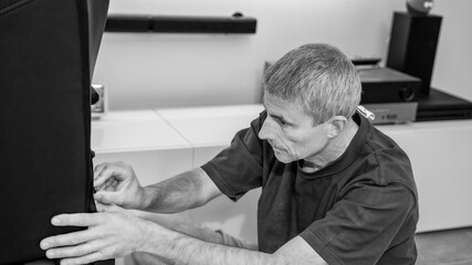 Man assembling new furniture at home, new purchase, hobby concept. Caucasian male mounting a gaming chair