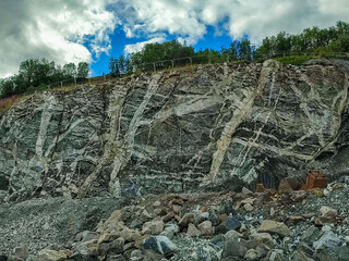 Abbruchkante eines Basalt-Steinbruchs, mit hellen Quarzadern durchzogen