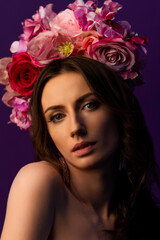 Fototapeta premium Portrait of an attractive young Ukrainian woman wearing a beautiful wreath of pink roses. Headdress for a girl. Concept wedding style or beauty salon and skin care.