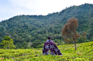 Fototapeta na wymiar Telaga Warna, Bogor, Indonesia – Novemer 22, 2020: Playing With Songket Fabric With Tea Garden Scenery In The Background. With Blured Background, Light Bokeh Background.