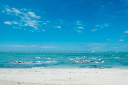 Wide and empty white sandy beach and seaside in sunny weather