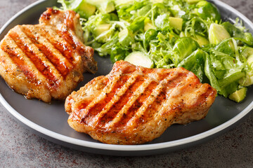 Healthy food grilled pork chop with fresh salad of avocado, brussels sprouts, lettuce close-up in a plate on the table. horizontal
