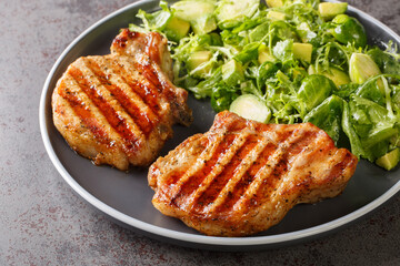Pork steak on a bone and green salad with brussels sprouts, avocado and herbs closeup in the plate on the table. Horizontal