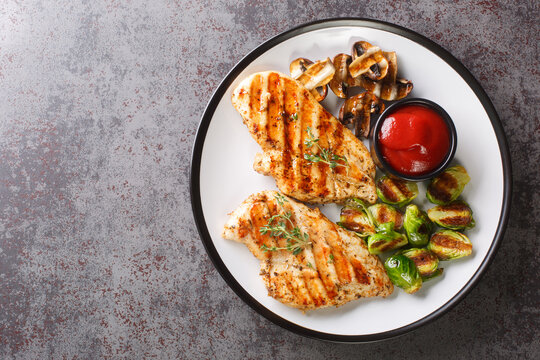 Healthy Food Grilled Chicken With Vegetables And Tomato Sauce Close-up In A Plate On The Table. Horizontal Top View From Above