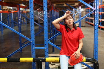 Portrait of warehouse workers young asian woman sitting and taking a break while wipe the sweat away after controlling stock and inventory in retail warehouse logistics, distribution center - obrazy, fototapety, plakaty