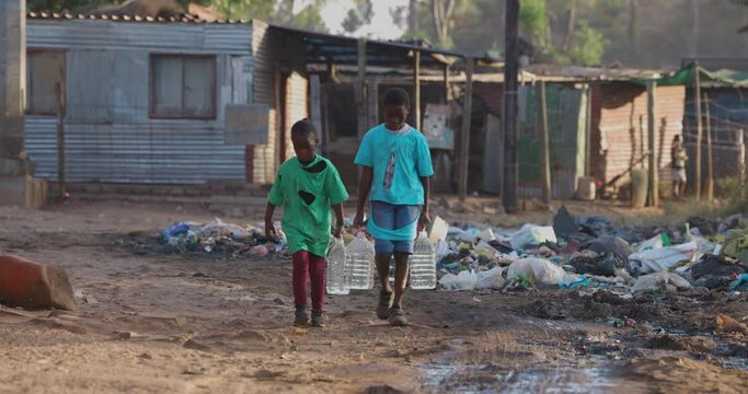Poverty.Inequality. Climate change.Close-up of two young black African children carrying water for domestic use. Poor living conditions and no access to clean running water.