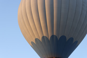 Hot air balloon flies on blue sky closeup