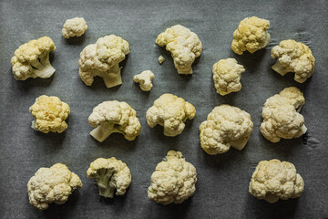 Raw cauliflower on parchment paper on the baking tray, ready to be baked