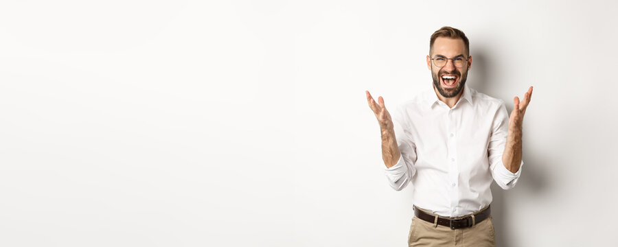 Frustrated and angry man screaming in rage, shaking hands furious, standing over white background