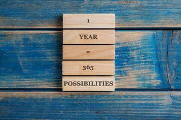 One year is 365 possibilities sign written on a stack of wooden pegs