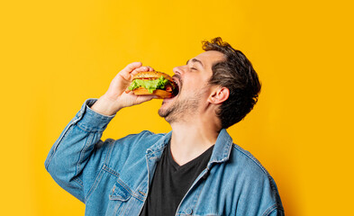 hungry man with burger on yellow background