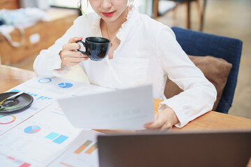 Fototapeta na wymiar woman working on a computer, budgeting documents and drinking coffee