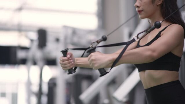 Sport woman using pulldown weight machine for back in a gym.