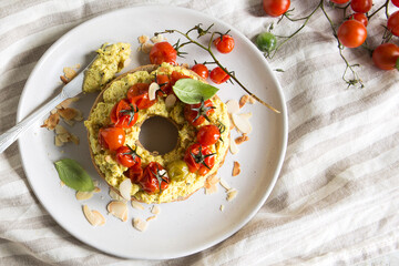 plate with bagel with tofu and baked tomatoes on the table