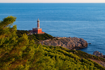 Red Lighthouse “Faro Di Punta Carena“ on the south west end of Capri Italy with moon and warm...
