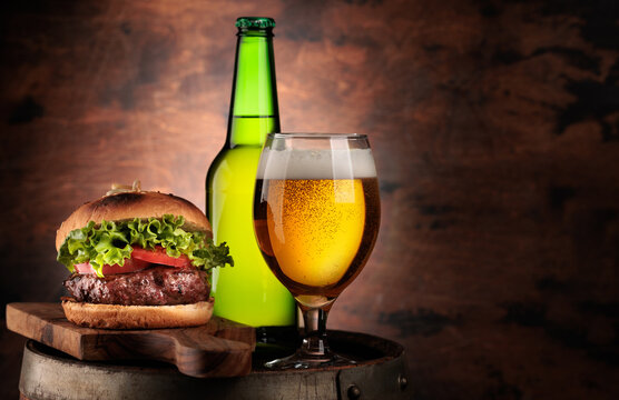 Draft beer glass and hamburger on wooden barrel