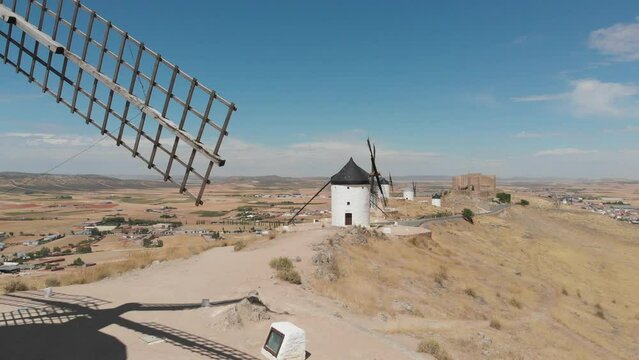 Windmills of La Mancha, Spain and castle in distance. Aerial view flying past blades.