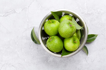 Fresh green apples in colander on stone table