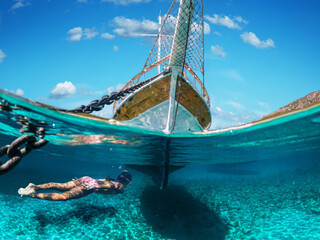 Girl diver is snorkeling on a beautiful sea beach. The bottom half of the picture is occupied by...