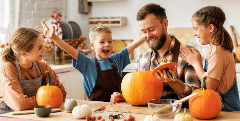 Happy family mother, father and kids  to remove pulp from from pumpkin while carving jack o lantern...