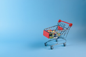 Buy medicine. Shopping basket with various medicinal, pills, tablets on blue background. Studio Photo