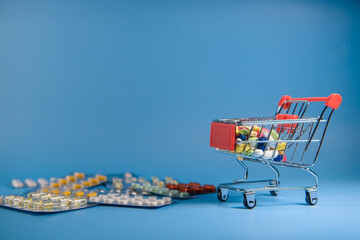 Buy medicine. Shopping basket with various medicinal, pills, tablets on blue background. Studio Photo