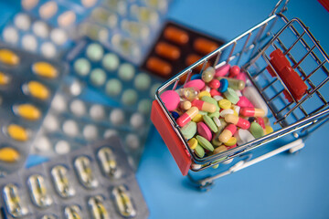 Buy medicine. Shopping basket with various medicinal, pills, tablets on blue background. Studio Photo