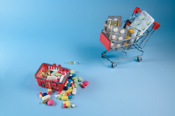 Buy medicine. Shopping basket with various medicinal, pills, tablets on blue background. Studio Photo
