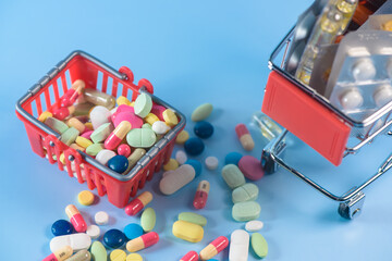 Buy medicine. Shopping basket with various medicinal, pills, tablets on blue background. Studio Photo